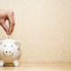 Hand dropping coin into white piggy bank