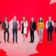 Group of people in a line superimposed on a bright red maple leaf background